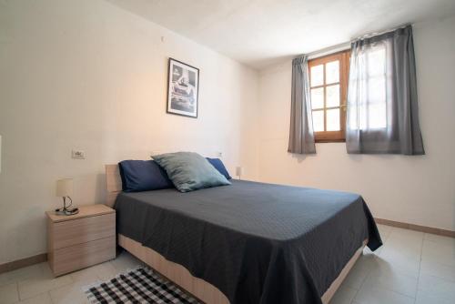 a bedroom with a bed with blue pillows and a window at Baccu Mandara Sea View Modern Villa with Parking! in Geremeas