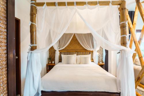 a bedroom with a canopy bed with white drapes at Baan Phuvara Retreat - Romantic Jacuzzi Mountain View Villas in Ao Nang Beach