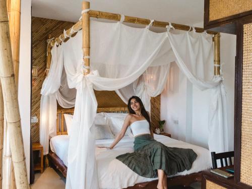 a woman is sitting on a bed at Baan Phuvara Retreat - Romantic Jacuzzi Mountain View Villas in Ao Nang Beach