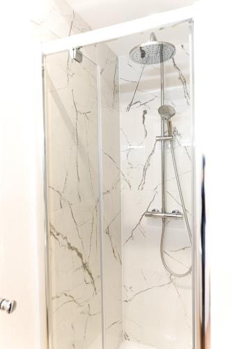 La salle de bains en marbre blanc est pourvue d'une douche. dans l'établissement Le Tropical - Beau logement centre - Gare - Tram, au Mans