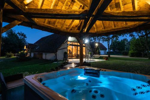 a jacuzzi tub under a wooden roof at Charmantes Maisons avec spas privatifs au calme Idéal weekend à 2 en famille ou entres amis in Vierzon