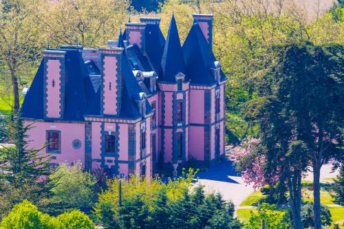 an old pink castle in the middle of trees at Château Hôtel Du Colombier in Saint Malo