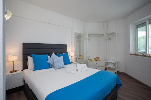 um quarto com uma cama grande e almofadas azuis em BeGuest Beachfront Apartment Caparica Lisbon em Costa da Caparica