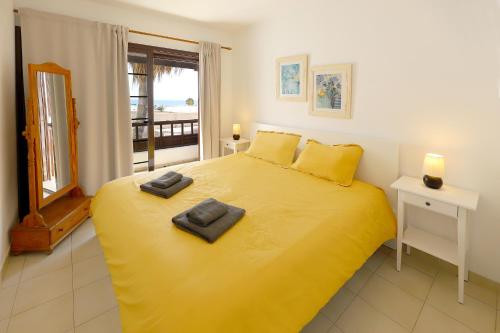 a bedroom with a yellow bed with two towels on it at Los Helechos A1, central 2 bed PDC in Puerto del Carmen