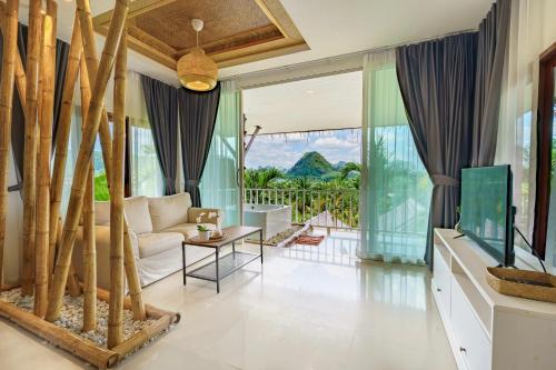 a living room with a couch and a tv at Baan Phuvara Retreat - Romantic Jacuzzi Mountain View Villas in Ao Nang Beach