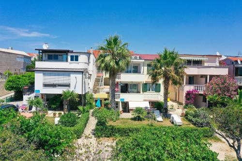 a building with palm trees in front of it at Rooms Malic in Petrcane