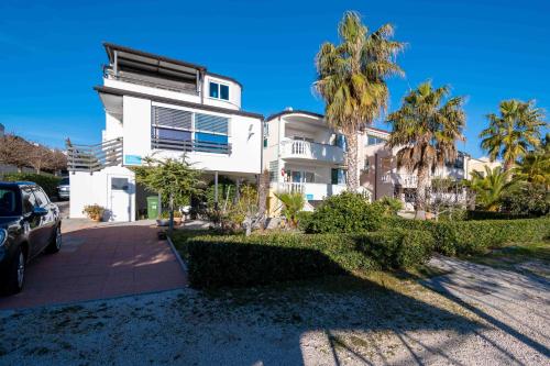 a white building with palm trees in front of it at Rooms Malic in Petrcane