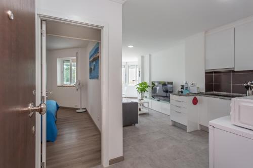 a kitchen with a hallway leading to a kitchen with white cabinets at BeGuest Beachfront Apartment Caparica Lisbon in Costa da Caparica
