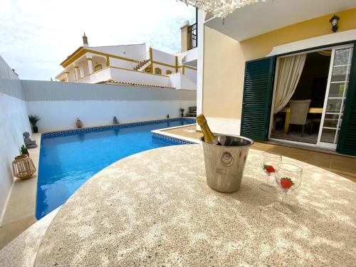 a pool with a table with a bottle of wine on it at Pêra Amazing Villa With Pool by Homing in Pêra