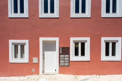 un edificio rojo con una puerta y ventanas blancas en Pardal RC B - Stylish Studio in Alcantara with free parking nearby, en Lisboa