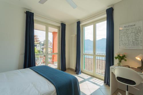 a bedroom with a bed and a desk and windows at Blue Bliss Apartment by Rent All Como in Colonno