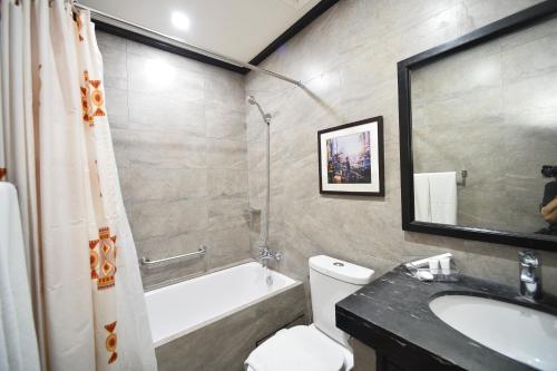 a bathroom with a sink and a toilet and a bath tub at Paragon Hotel and Suites in Baguio