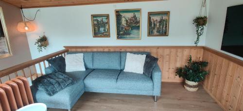a living room with a blue chair and pictures on the wall at The Kontor in Sandavágur