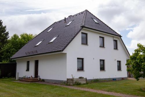 ein weißes Haus mit schwarzem Dach in der Unterkunft Urlaubs-Appartement am Dorfrand in Wieck