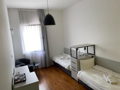 a bedroom with two beds and a desk and a chair at Osten Art Hotel in Skopje