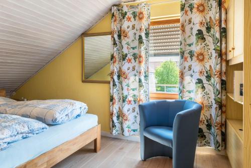 a bedroom with a bed and a blue chair at Jaulneau in Owingen