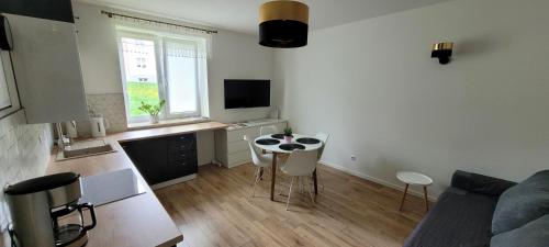 a living room with a couch and a table and a kitchen at Apartament Przy Bocznej in Kowary