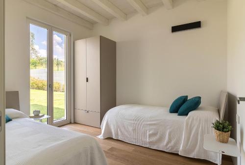 een witte slaapkamer met 2 bedden en een raam bij Cittadella 7 in Manerba del Garda