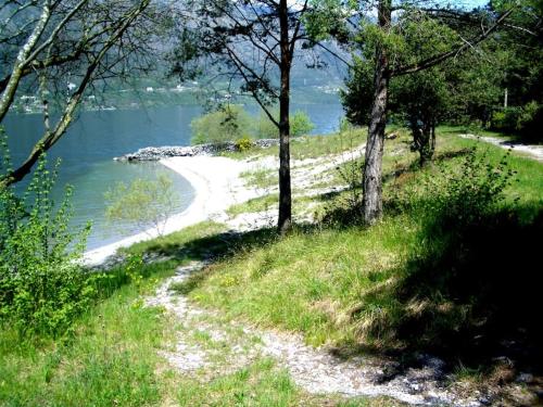 un chemin menant à une plage située à côté d'une étendue d'eau dans l'établissement Villa (home C) — Pool — Lake Idro, à Vesta