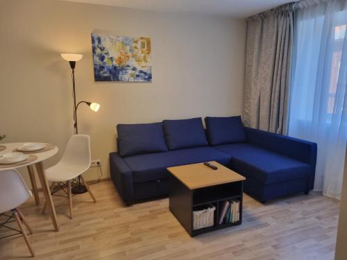 een woonkamer met een blauwe bank en een tafel bij Park Alice Apartment in Liepāja