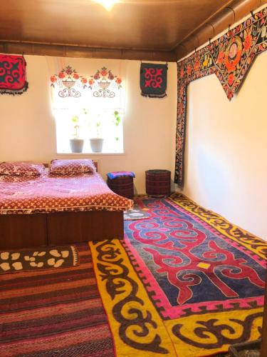 a bedroom with a bed and a rug at Tilek Guest House in Sary-Mogul