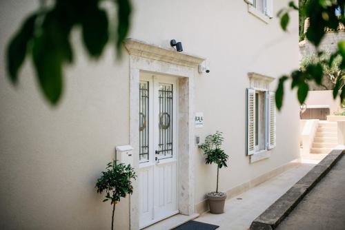a white house with a door and two potted plants at KALA LUXURY ROOMS by DuHomes in Dubrovnik