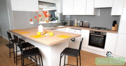 a kitchen with a counter with chairs and a table at 4-5 Bedroom House Garden Lots of Parking 15 min to city Close to motorway in Girton