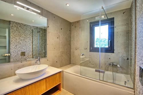 a bathroom with a sink and a tub and a mirror at Villa Acropolitana by PosarelliVillas in Acharavi