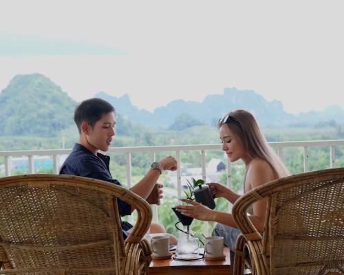 Un uomo e una donna seduti a un tavolo di Baan Phuvara Retreat - Romantic Jacuzzi Mountain View Villas ad Aonang Beach