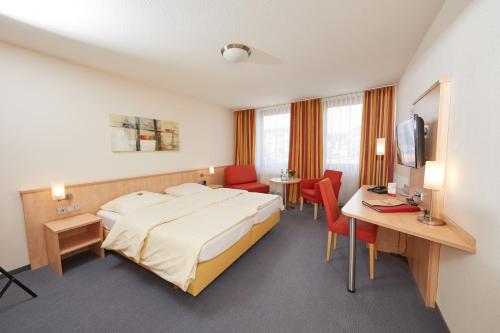 Habitación de hotel con cama, escritorio y TV. en Hotel Filderland - Stuttgart Messe - Airport - Self Check-In, en Leinfelden-Echterdingen