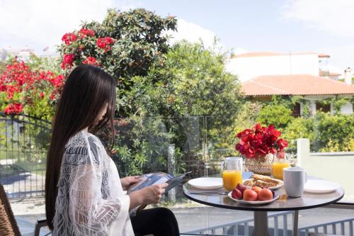 Notos Premium Holiday Apartments في بيفكوهوري: امرأة تجلس على طاولة مع طبق من الطعام