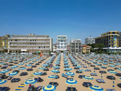 une plage remplie de parasols et de bâtiments bleus et blancs dans l'établissement Hotel Boston 3 Stelle Superior Frontemare, à Lido di Jesolo