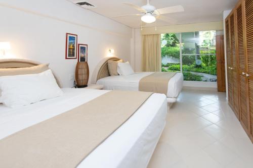 a bedroom with two beds and a window at Las Villas Akumal in Akumal