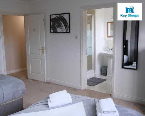 a bedroom with a bed and a television and a bathroom at Huge House At Keysleeps Short Lets Milton Keynes With Free Parking Contractor Leisure in Loughton