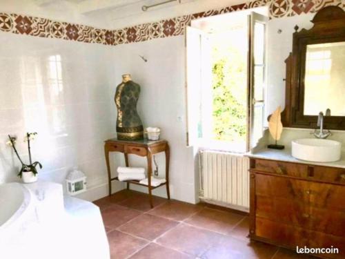 une salle de bain avec un lavabo, un miroir et une fenêtre dans l'établissement Domaine de Ménerque - petit château avec piscine, à Lisle-sur-Tarn