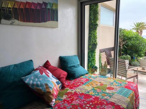 a bed with colorful pillows sitting on a balcony at PARENTHÈSE NATURE in Canet-en-Roussillon