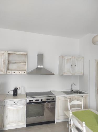 a white kitchen with a stove and a sink at Deluxe Family Suite in San Menaio