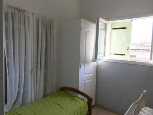 une chambre avec un lit vert et une fenêtre dans l'établissement MARSEILLAN PLAGE JOLI T2, à Marseillan