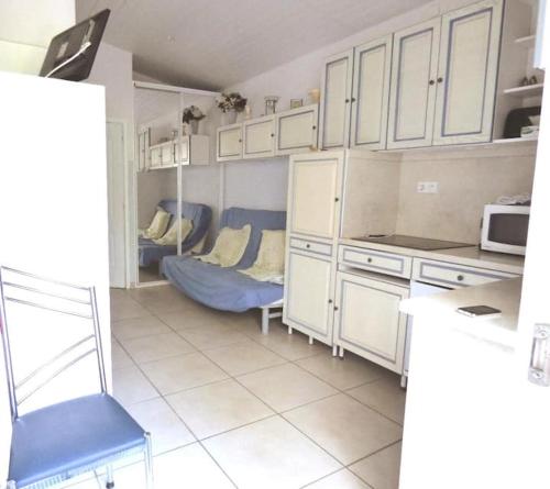 une cuisine avec des placards blancs et une chaise bleue dans l'établissement MARSEILLAN PLAGE JOLI T2, à Marseillan