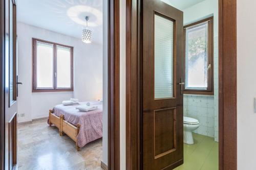 a door to a bedroom with a bed and a toilet at Villetta al Torchio Artemide in Manerba del Garda