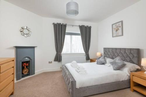 una camera con un grande letto e un camino di Four Oaks Cottage a Rockcliffe