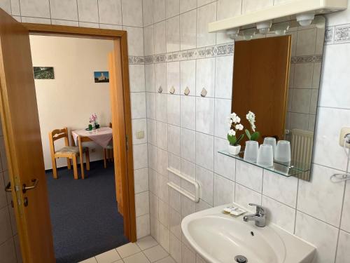 ein Bad mit einem Waschbecken und einem Tisch in einem Zimmer in der Unterkunft Hotel Nordwind in Lohme