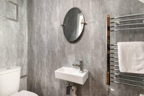 un bagno con un water, un lavandino e uno specchio di Four Oaks Cottage a Rockcliffe