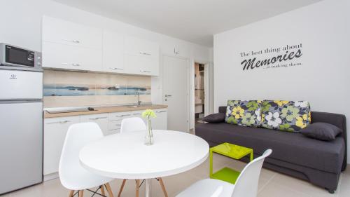 a kitchen and living room with a white table and a couch at Apartments Memories in Baška