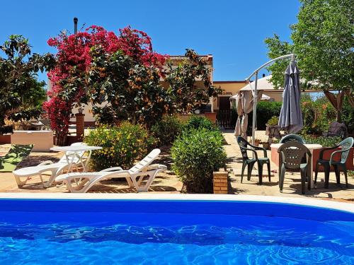 una piscina con sillas, mesa y sombrilla en Finca-Vallestares, en Almonte