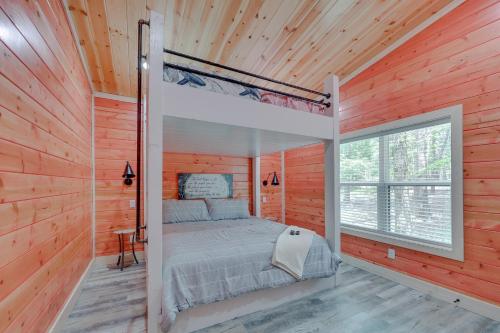 ein Schlafzimmer mit einem Bett in einer Holzwand in der Unterkunft Family-Friendly Broken Bow Home with Deck and Grill! in Broken Bow