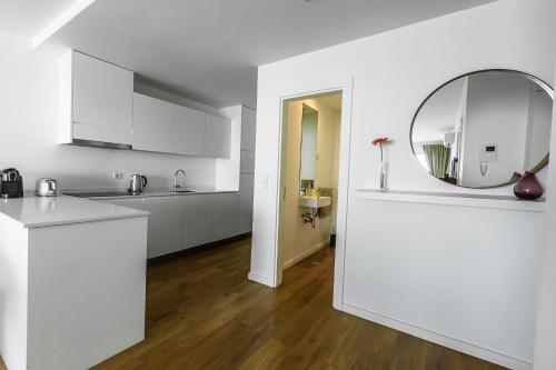 a white kitchen with a mirror and a counter at Xenon Urban Apartments in Maputo