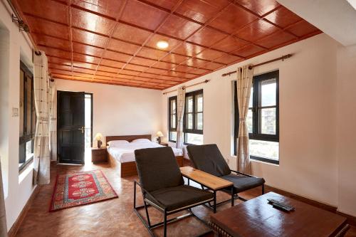 a bedroom with a bed and two chairs and a table at Himalayan Hideaway in Tanahun