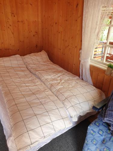 uma cama num quarto de madeira com uma janela em Holiday Raustua Cabin em Gol