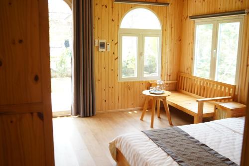 a bedroom with a bed and a table and windows at BH Villa Lăng Cô Huế in Lang Co